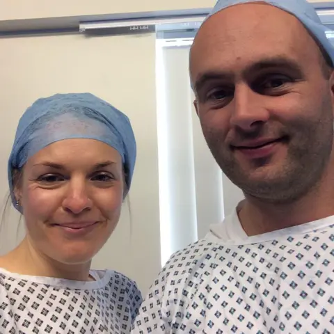 Family photo Annika and husband Eulyn smile for the camera, and wear medical gowns, during IVF treatment before their son was born in 2018. 